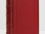 a red book sitting on top of a table next to a white wall