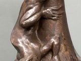 une statue en bronze représentant un homme et un chien, posée sur un vase