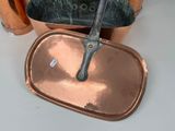 two copper pans and a knife sitting on a table