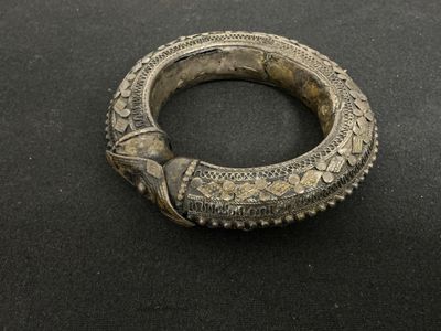 gros plan d'un bracelet en argent sur une surface noire