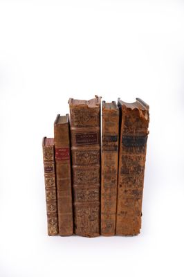 several old books are stacked on top of each other on a white surface