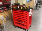 a red tool box with tools on it in a garage