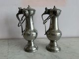 two silver vases sitting on a marble counter top