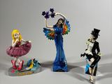 three figurines of a woman in a dress and a man in a top hat