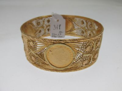 Gros plan sur un bracelet en or orné d'une pièce de monnaie