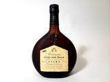 une vieille bouteille d'alcool posée sur une surface blanche
