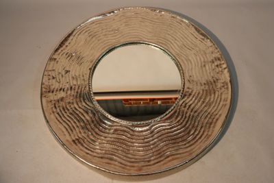 a silver plate with a mirror on it on a table