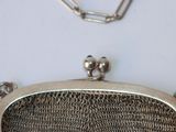 a silver purse with a chain around it on a table
