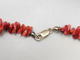 a close up of a necklace with red coral beads on a mannequin