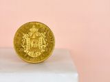 a close up of a gold coin sitting on top of a white pedestal