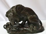 bronze statue of a lion on a rock with a white background