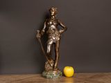 a statue of a man holding a stick and a lemon on a table