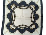 a black and white square scarf with a gold border