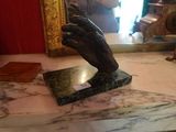une statue représentant une main tenant un livre posé sur une table en marbre
