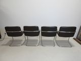 four black leather chairs are lined up against a white wall