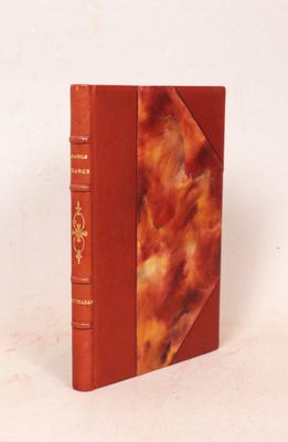 un livre orange posé sur une table blanche, près d'un mur blanc