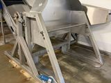 a metal conveyor belt in a garage with a blue bucket