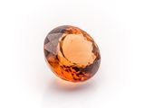 a close up of an orange sapphire stone on a white surface