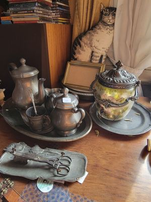a wooden table topped with silverware and a cat sitting on top of it