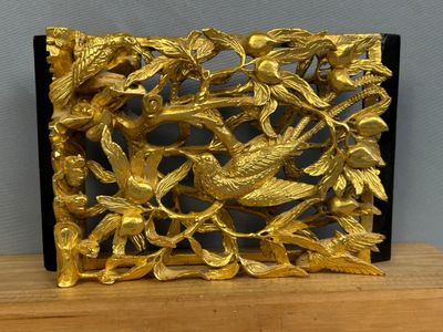 a gold plate with birds and leaves on it