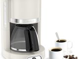 a white coffee maker with a cup of coffee next to it