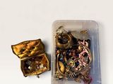 a small container filled with assorted jewelry on a white surface