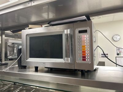 un micro-ondes argenté posé sur un plan de travail dans une cuisine