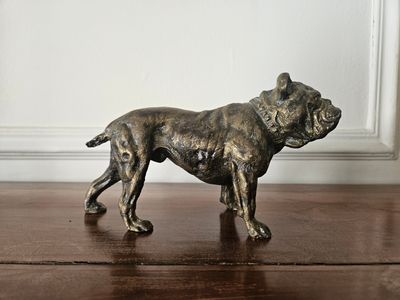 une statue en bronze représentant un chien, posée sur une table en bois