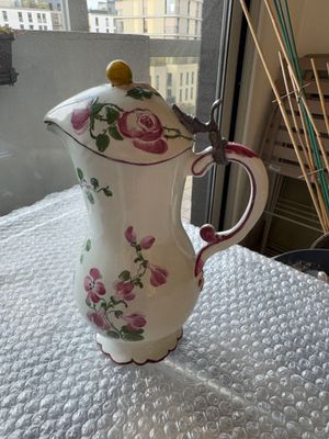 un pichet blanc orné de fleurs roses, posé sur une table