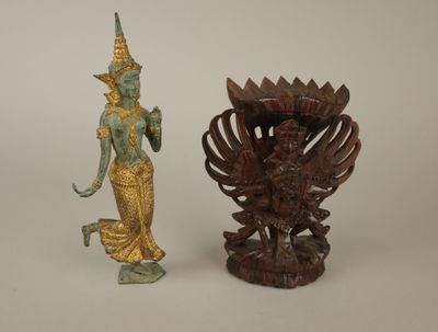 une statue représentant une femme debout à côté d'un vase posé sur une table