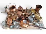 une pile de vieux faitouts et casseroles en cuivre posée sur un plateau en bois