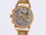 a close up of a gold watch with a chain around it