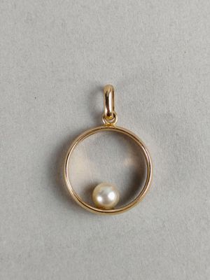a gold pendant with a pearl inside of it