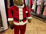 un ours en peluche déguisé en Père Noël dans un magasin de vêtements