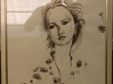 drawing of a woman ' s face in a gold frame on a table