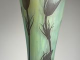 a glass vase with flowers painted on it on a table