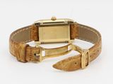 an image of a wrist watch with a gold case and brown leather strap