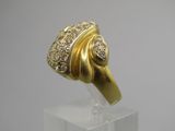une photo d'une bague en or et diamants posée sur un socle transparent