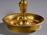 an antique brass candle holder with a candle on top of it