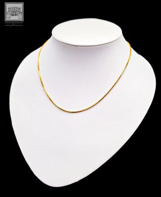 un collier en or autour du cou d'un mannequin, sur fond noir