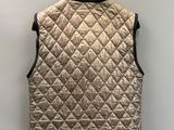 a gold quilted vest hanging on a clothes hanger