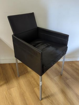 une chaise noire posée sur un parquet en bois dur