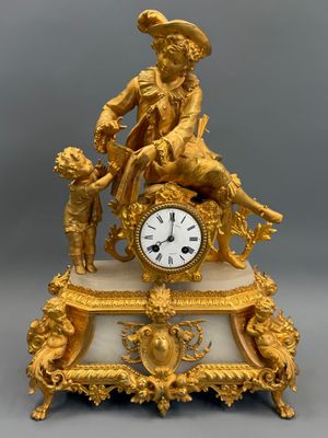 a gold clock with a man sitting on top of it
