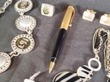 a pen sitting on top of a table next to a bunch of jewelry