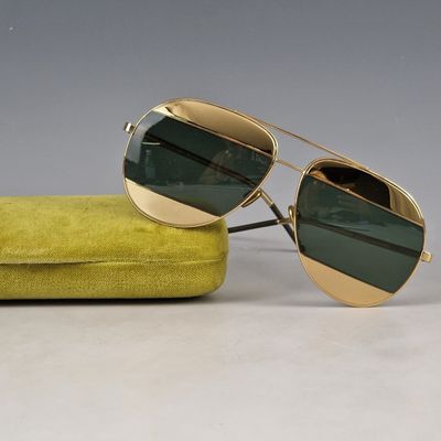pair of gold sunglasses with green lenses sitting on a yellow case