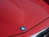 a close up of a red car with a chrome emblem on it
