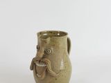 a brown vase with a mustache on it on a white surface