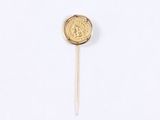 a close up of a gold coin on a stick on a white surface