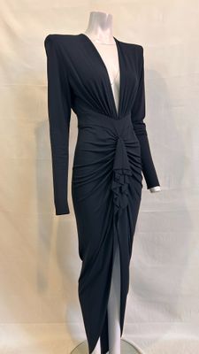 La robe est noire, à manches longues et avec un col en V.