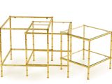 trois tables d'appoint en métal doré et en verre sur fond blanc
